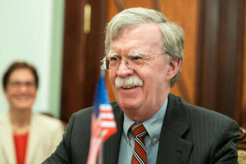 Man with glasses smiling near small American flag