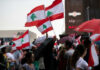 Crowd waving Lebanese flags at outdoor gathering