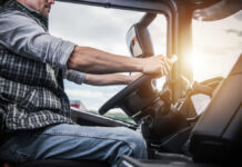 A truck driver gripping the steering wheel inside a vehicle cabin