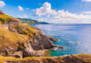 Scenic view of rocky cliffs meeting the ocean under a blue sky