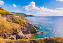 Scenic view of rocky cliffs meeting the ocean under a blue sky