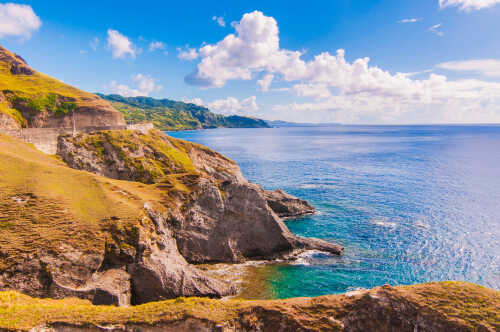 Scenic view of rocky cliffs meeting the ocean under a blue sky