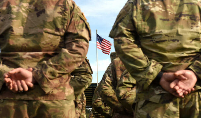 American,Soldiers,And,Flag,Of,Usa.,Us,Army.,Veteran,Day Soldiers standing in formation with an American flag in the background