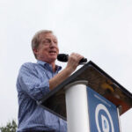 Speaker at a podium addressing an audience outdoors