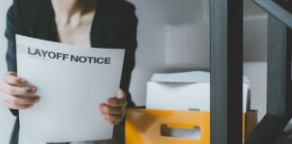 Person holding a layoff notice in an office setting
