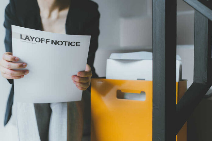 Person holding a layoff notice in an office setting