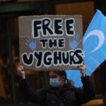 Person holding a sign that reads 'FREE THE UYGHURS' during a protest
