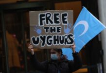 Person holding a sign that reads 'FREE THE UYGHURS' during a protest