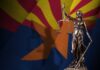 Statue of Lady Justice in front of the Arizona state flag