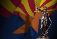Statue of Lady Justice in front of the Arizona state flag