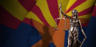 Statue of Lady Justice in front of the Arizona state flag
