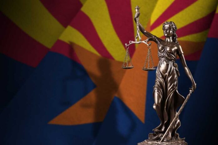 Statue of Lady Justice in front of the Arizona state flag