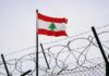 Lebanon’s Bold Stand Against Iranian Forces Lebanese flag waving next to barbed wire fence