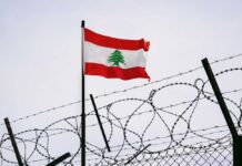 Lebanese flag waving next to barbed wire fence