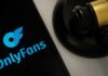 OnlyFans logo displayed on a smartphone next to a gavel