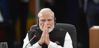 A leader with folded hands sitting at a conference table