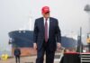 Trump’s China Visit: Pageantry Over Progress? A man in a suit wearing a red cap stands near a ship at a harbor
