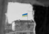 Ground Robots Cut Casualties: Ukraine’s Bold Plan Ukrainian flag over apartment building seen through a dark frame