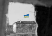 Ground Robots Cut Casualties: Ukraine’s Bold Plan Ukrainian flag over apartment building seen through a dark frame