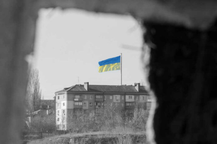 Ukrainian flag over apartment building seen through a dark frame