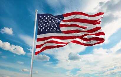 American flag waving on a flagpole against a blue sky with clouds