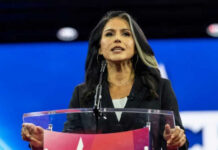 CIA Clash? Tulsi Exit Mystery Deepens Person speaking at a podium during an event.