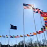 NATO’s Nuclear Shield May Reach Poland and the Baltics Many national flags flying in clear blue sky