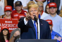 Collins Gets Trump Boost—Upends Maine Race Man speaking at rally with crowd behind him
