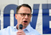 Man with glasses speaking into a microphone