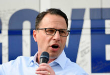 Man with glasses speaking into a microphone
