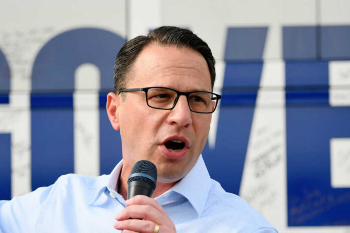 Man with glasses speaking into a microphone