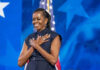 Person standing in front of American flag smiling