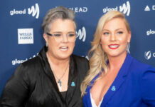 Two women pose together on a blue event backdrop