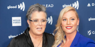 Two women pose together on a blue event backdrop
