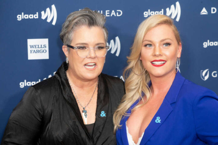 Two women pose together on a blue event backdrop