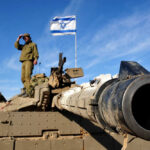 Missiles Rain on Israel as Trump Draws Red Line Soldier saluting from atop a tank with an Israeli flag in the background