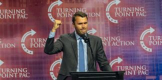 Speaker at podium raising a fist during a conference