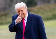 Media Meltdown Over Quiet DNI Hand-Off A man in a dark coat and pink tie giving a thumbs up outdoors