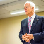 GOP Meltdown: Cornyn Warns ‘DISASTER’ A man in a suit delivering a speech in a conference room