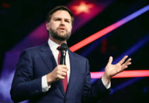 Washington’s $6B Address Scandal: 400 Contractors Flagged Man in suit speaking with microphone on stage.