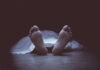 Feet protruding from under a white sheet.