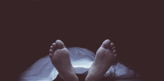 Feet protruding from under a white sheet.