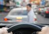 Shelters Overrun — Car Camp Survival Begins Driver’s hands on steering wheel as a pedestrian crosses in front of a car in traffic