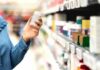Shopper holding a pill bottle in a pharmacy aisle