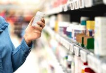 Shopper holding a pill bottle in a pharmacy aisle