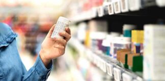 Shopper holding a pill bottle in a pharmacy aisle