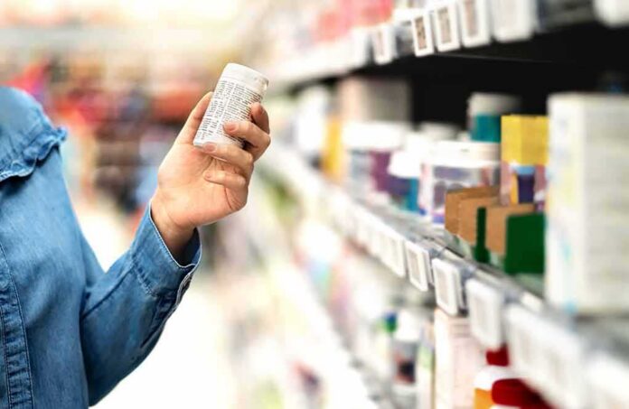 Shopper holding a pill bottle in a pharmacy aisle