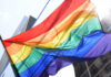 Ports Shut Out LGBTQ Cruise A vibrant rainbow flag waving against a city backdrop