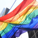 Ports Shut Out LGBTQ Cruise A vibrant rainbow flag waving against a city backdrop
