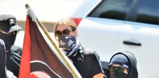 Masked protesters holding a black and red flag